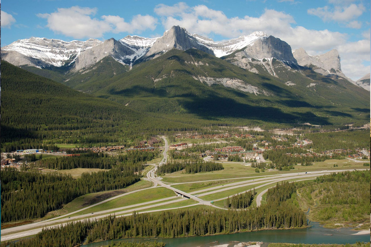 Scenic highway beneath snow-covered Rocky Mountains in Canmore, Alberta.